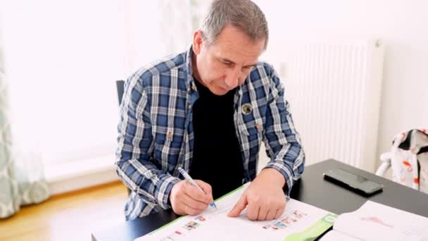 Mann Mittleren Alters Karierten Hemd Sitzt Tisch Schreibt Aufgaben Lehrbuch — Stockvideo