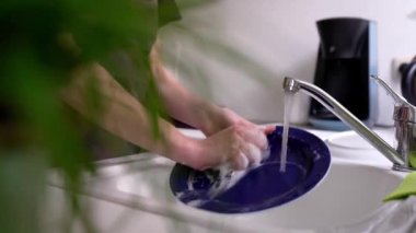 Kahverengi şeflerin önlüklü kadın bulaşık deterjanıyla süngerle yıkıyor, mutfakta lavaboda. konsept temizlik, bulaşık yıkama, bulaşık makinesi