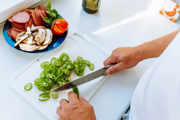 Stock image Mans hands cut peppers with knife on cutting board, slicing ingredients for pizza or salad