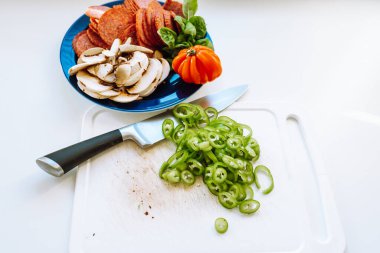 Kesme tahtasında dilimlenmiş kırmızı biber, mutfak bıçağı, yemek pişirmek için dilimlenmiş yemek.