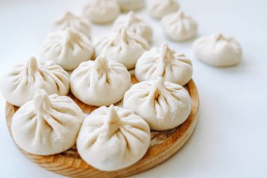 Pişirmeden önce Khinkali. Yuvarlak tahta üzerinde ev yapımı khinkali hamur tatlısı yığını. Khinkali pişirmeden önce, el yapımı. Gürcü yemekleri