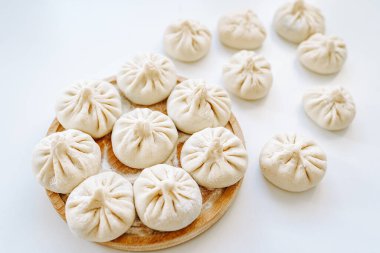 Pişirmeden önce Khinkali. Yuvarlak tahta üzerinde ev yapımı khinkali hamur tatlısı yığını. Khinkali pişirmeden önce, el yapımı. Gürcü yemekleri