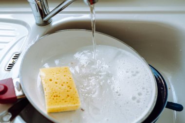 Mutfak lavabosunda seramik kaplama ile yanmış tava, bulaşıkları elle yıkamak, deterjan önleyici deterjanla yıkamak.