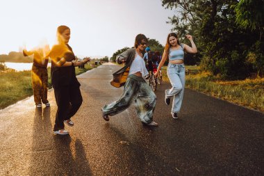 Doğada eğlenen genç kızlar. Genç kadınlar, genç kızlar, sırıtan, yağmurdan sırılsıklam olmuş saçlarıyla, eğlenen, nehirde selfie çeken ve dans eden güneş ışınları, parıldayan lensler...