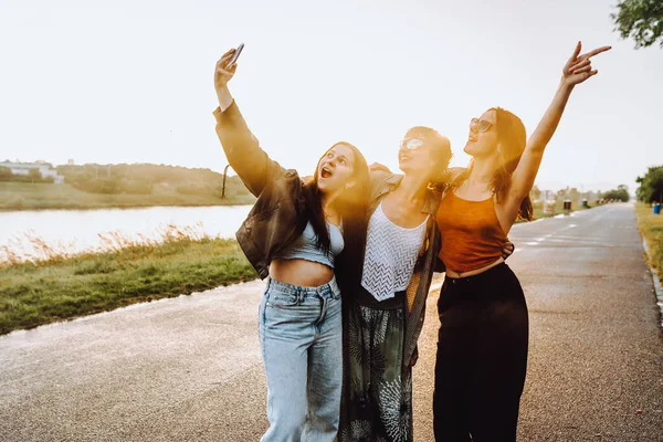 stock image party young happy girls in nature. company young women, teenage girls, smiling, with hair wet from rain, having fun, taking selfies and dancing in nature by river, in rays of setting sun, glare lens