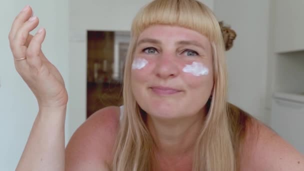 Atrakcyjna Kobieta Średnim Wieku Blondynka Długimi Włosami Rozmazuje Nawilżacz Twarzy — Wideo stockowe
