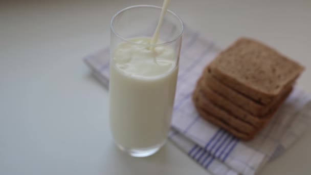 スローモーションはキッチンテーブルの上にミルクを注ぐ 朝食には生乳と生パン — ストック動画