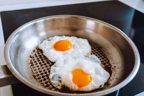 焼いた金属グリルパンの鍋に2個の卵を揚げる 揚げたタンパク質とクリスピーな粉末 液体の卵黄のクローズアップ 高角度のビューとフライドエッグ 金属グリルパンの揚げ卵 — ストック写真