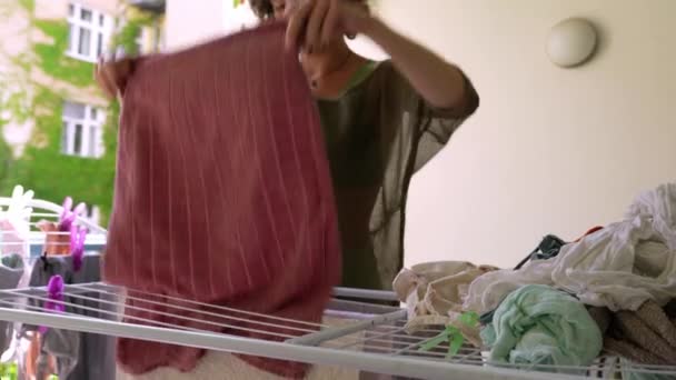 把湿衣服挂在烘干机上 挂在房子的阳台上 T恤衫 帮助做家务活 — 图库视频影像