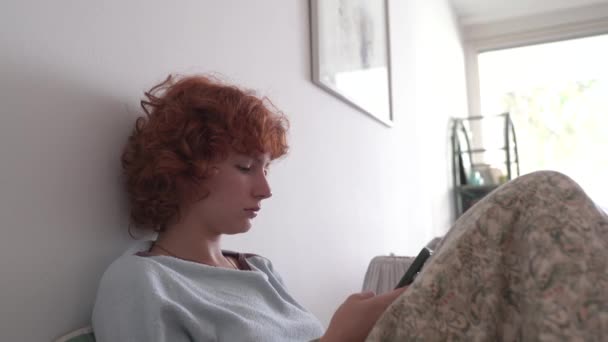 Curly Red Haired Teen Girl Pajamas Sits Bed Uses Mobile — Stock Video