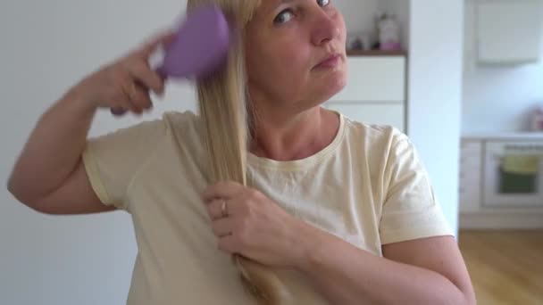 Καμπυλωτή Μεσήλικη Γυναίκα Χτενίζει Μακριά Ίσια Ξανθά Μαλλιά Επιδεικνύοντας Υγιή — Αρχείο Βίντεο