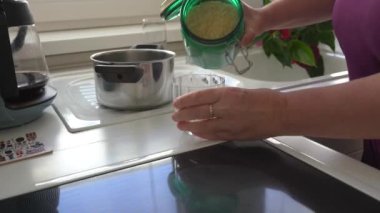 Kadın pilavı cam ölçülerde ölçer, cam çevre dostu kavanozdan pirinç döker, pilav pişirir.