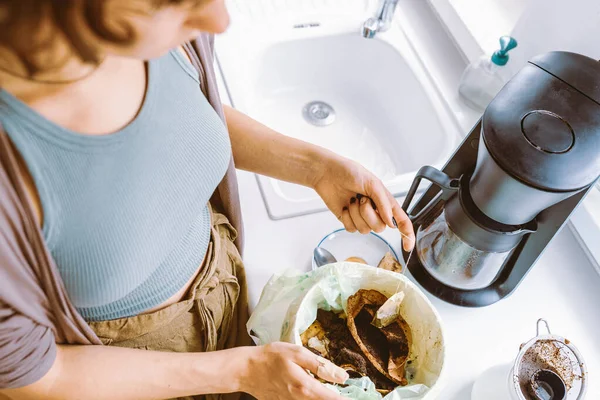 Close-up, different angles, young woman throwing used tea bag into food waste container in home kitchen. Sorting waste at home, recycling, composting