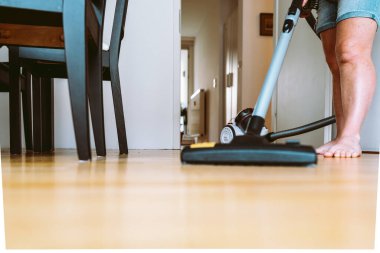 Kadın, parke döşemeli ve elektrikli süpürgeyle apartmanı temizliyor. Evde yalın ayak süpürme parke döşemesi