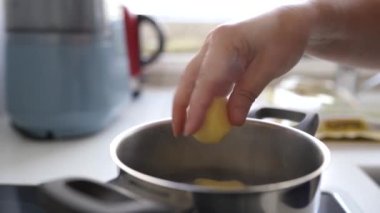 Ev mutfağında haşlanmış patates pişirmek. Kadın haşlanmış suya çiğ patates koyar, karıştırır, tuzlar, kontrol eder.