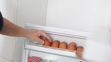 Yakın plan kadınlar buzdolabında yumurta yumurtlayan tavuklara el atarlar. Yemek hazırlıyorum.