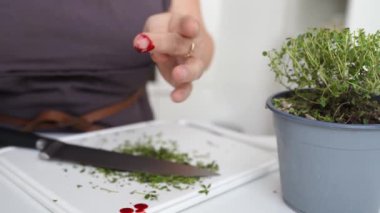 Kadın aşçı, parmaklarını keskin bıçakla keserken parmaklarını kesiyor. Parmaklarından kan akıyor. Mutfak bıçağıyla kesilmiş parmak kanaması.