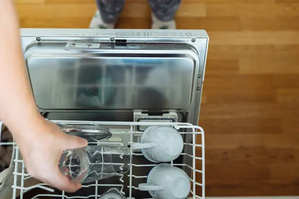 Top view of womans hand putting dirt in dishwasher