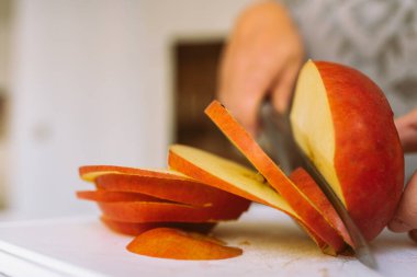 Kadınların eli, olgun elmaları dilimlemek için mutfak bıçağı kullanır. Elma cipsi yapmak için, turta pişirmek için..