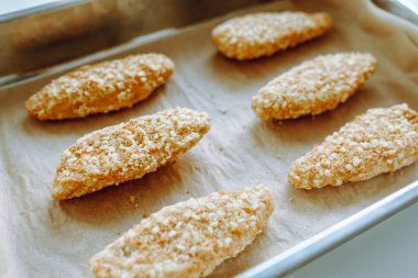 Fırın tepsisinde çiğ, donmuş tavuk parçaları. Ev yapımı nugget 'lar için yarı bitmiş ürünler