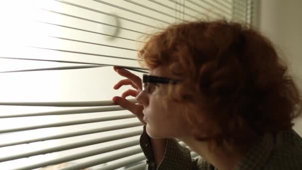 Adolescente Com Cabelo Encaracolado Usando Óculos Olha Curiosamente Para Fora — Vídeo de Stock