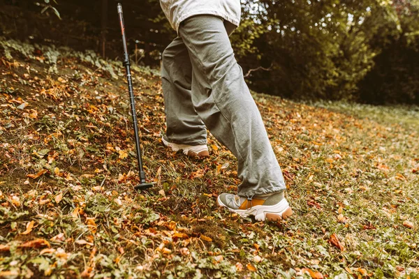 Nordic Walking in Autumn forest, hiking teenage girl. adventure and exercise concept, womens hiking, legs in comfortable hiking shoes and Nordic walking poles in autumn nature