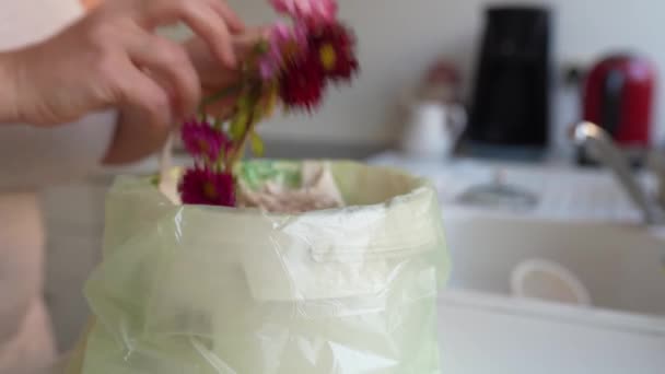 女人在家里的厨房里把干枯的菊花扔进生物废桶里 — 图库视频影像
