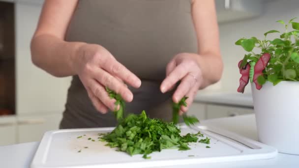 女性は専門的に家の台所で鋭い台所のナイフが付いている切断板のハーブを切ります 準備スパイス 調味料乾燥ハーブ パーズリー ハーブ — ストック動画