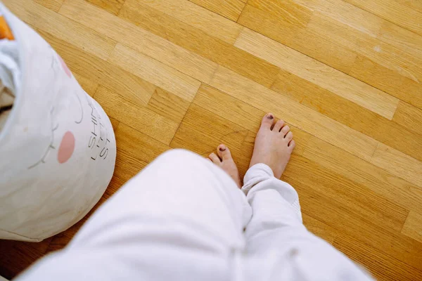 Top view bare female feet with bruised toenail, fungal disease, damaged big toes, standing on wooden floor during daytime, legs unknown woman, high angle copy space, freedom and relaxation concept