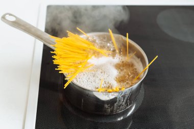 Kaynar suda kaynamış spagetti, tencerede, seramik hob 'da.