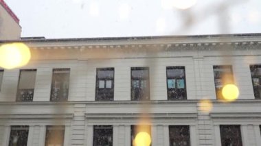 Arka planda kar yağışlı pencereler, neşeli çelenkleri aydınlatıyor. Yavaş çekim