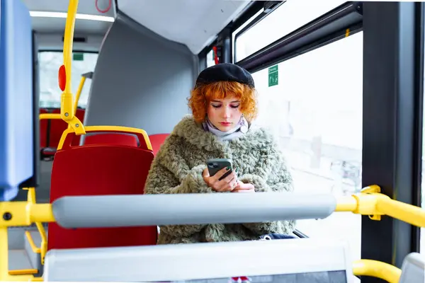 portrait young woman with bright makeup, manicure, dressed up, wearing beret, green fur coat, using phone, on bus
