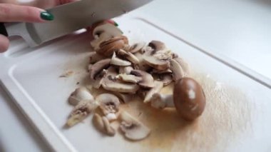 Kesme tahtasında şampiyon mantarları dilimlemek. yakın plan