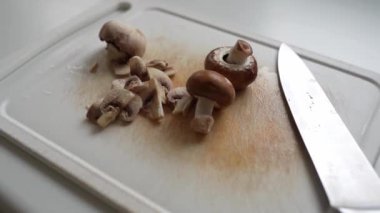 Kesme tahtasında şampiyon mantarları dilimlemek. yakın plan
