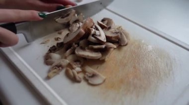 Kesme tahtasında şampiyon mantarları dilimlemek. yakın plan