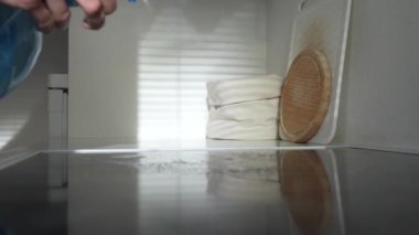 Mutfakta deterjanla çamaşır yıkamak, sprey şişesinden mutfak temizleyicisi sıkmak. Evde temizlik ve hijyen.