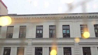 Arka planda kar yağışlı pencereler, neşeli çelenkleri aydınlatıyor. Yavaş çekim
