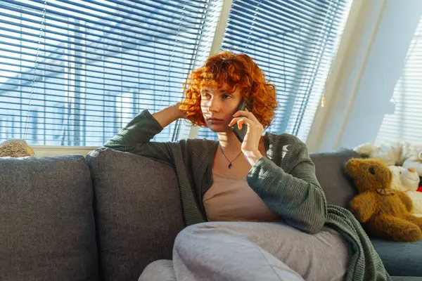 Retrato Vermelho Cabelos Encaracolados Adolescente Usando Telefone Enquanto Sentado Sofá — Fotografia de Stock
