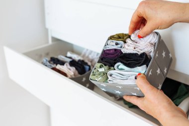 Kadın elleri iç çamaşırlarını katlayıp göğüs çekmecelerinde depolama organizatörü konteynırına koyuyor.