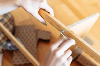 Ev eşyası montajı. Yakın plan genç kadın elleri tornavidayla mobilyalara vidalanıyor.