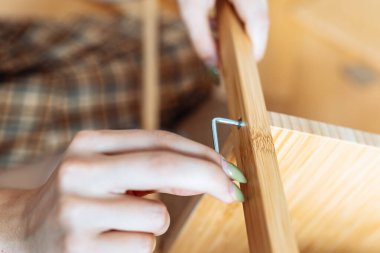 Ev eşyası montajı. Yakın plan genç kadın elleri tornavidayla mobilyalara vidalanıyor.