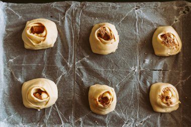 Tarçınlı ve şekerli rulo fırında pişirin. Tarçınlı rulo yapma işlemi. Hamur ekmek çarşafında, çörek şeklinde.