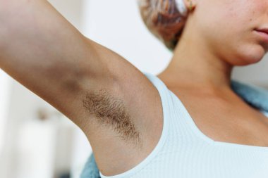 Vücut pozitifliği, feminizm, uzun koltuk altı kılları, kollarını kaldırmış bir kız.