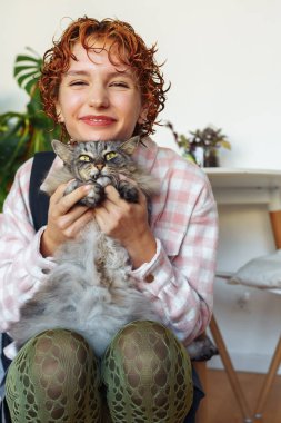 Kızıl saçlı, genç ve gri kedili çekici bir kadının portresi. bir evcil hayvan, bakım, sevgi ile pozitif iletişim