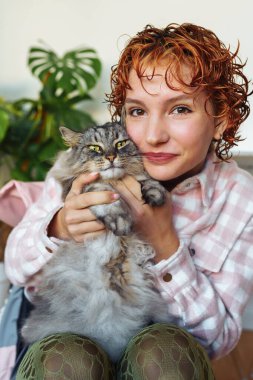 Kızıl saçlı, genç ve gri kedili çekici bir kadının portresi. bir evcil hayvan, bakım, sevgi ile pozitif iletişim