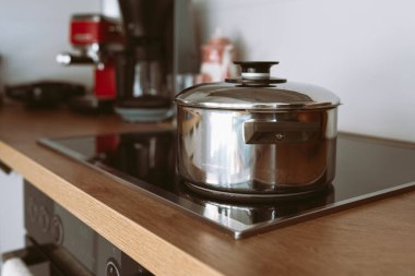 Cam mutfak hob, modern mutfak, ahşap yüzey kapaklı parlak metal tencere.
