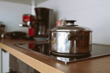 Cam mutfak hob, modern mutfak, ahşap yüzey kapaklı parlak metal tencere.