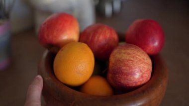 Mutfak masasındaki ahşap kasede olgun kırmızı elmalar. Meyveler tabakta
