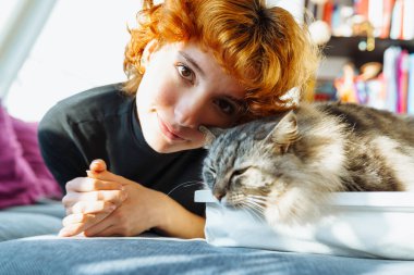 Portre kızıl saçlı, çekici genç bir kadın pofuduk büyük kediyle sarılıyor. Şefkat gösterisi, mırıldayan büyük kedi. evcil hayvanla arkadaşlık