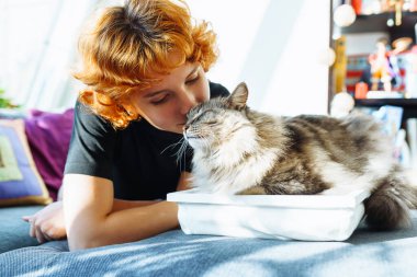 Portre kızıl saçlı, çekici genç bir kadın pofuduk büyük kediyle sarılıyor. Şefkat gösterisi, mırıldayan büyük kedi. evcil hayvanla arkadaşlık